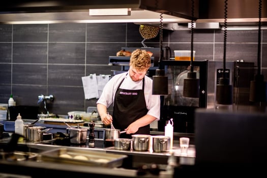Professional male chef working alone in commercial kitchen.